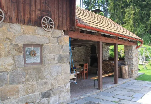 Dřevěná pergola u vchodu do chalupy Pazderna se zahradním posezením v létě