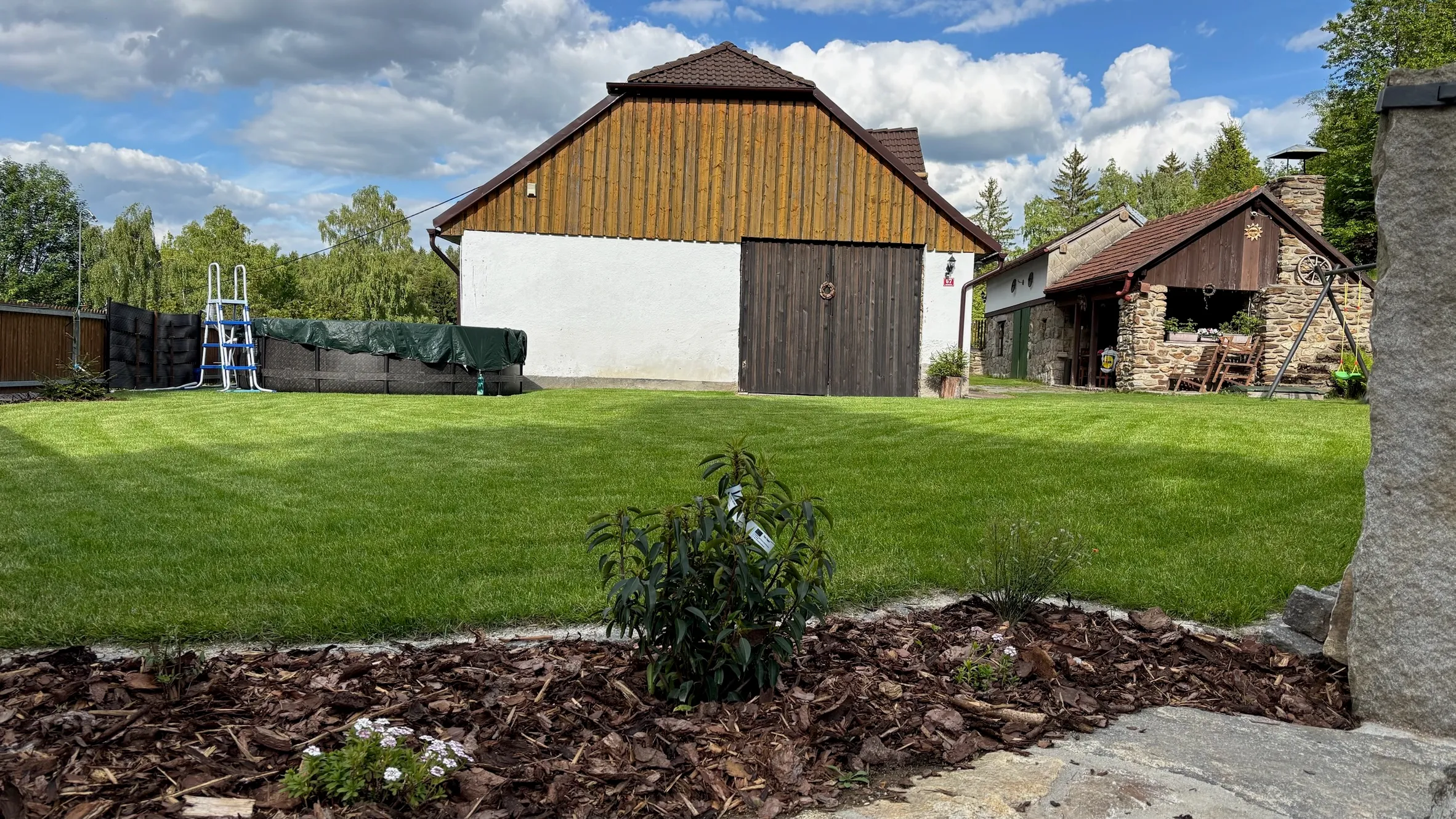 Detail štítu chalupy Pazderna s pohledem na trávník