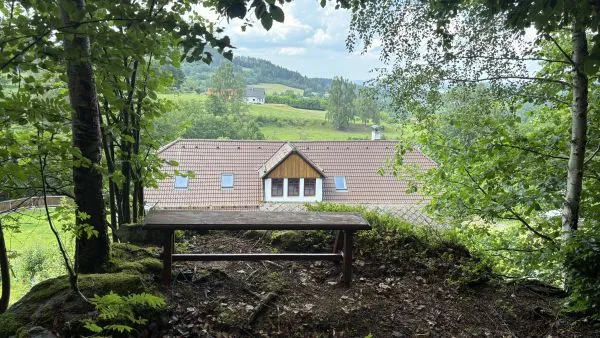 Výhled z lesního altánu nad střechou chalupy Pazderna na zelené údolí a šumavskou krajinu